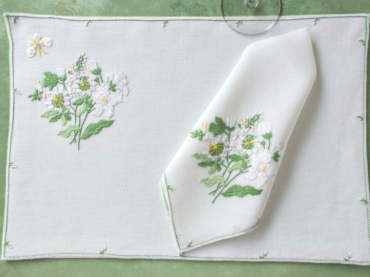 Single Rapisardi placemat and matching napkin showing white floral embroidery and butterfly.