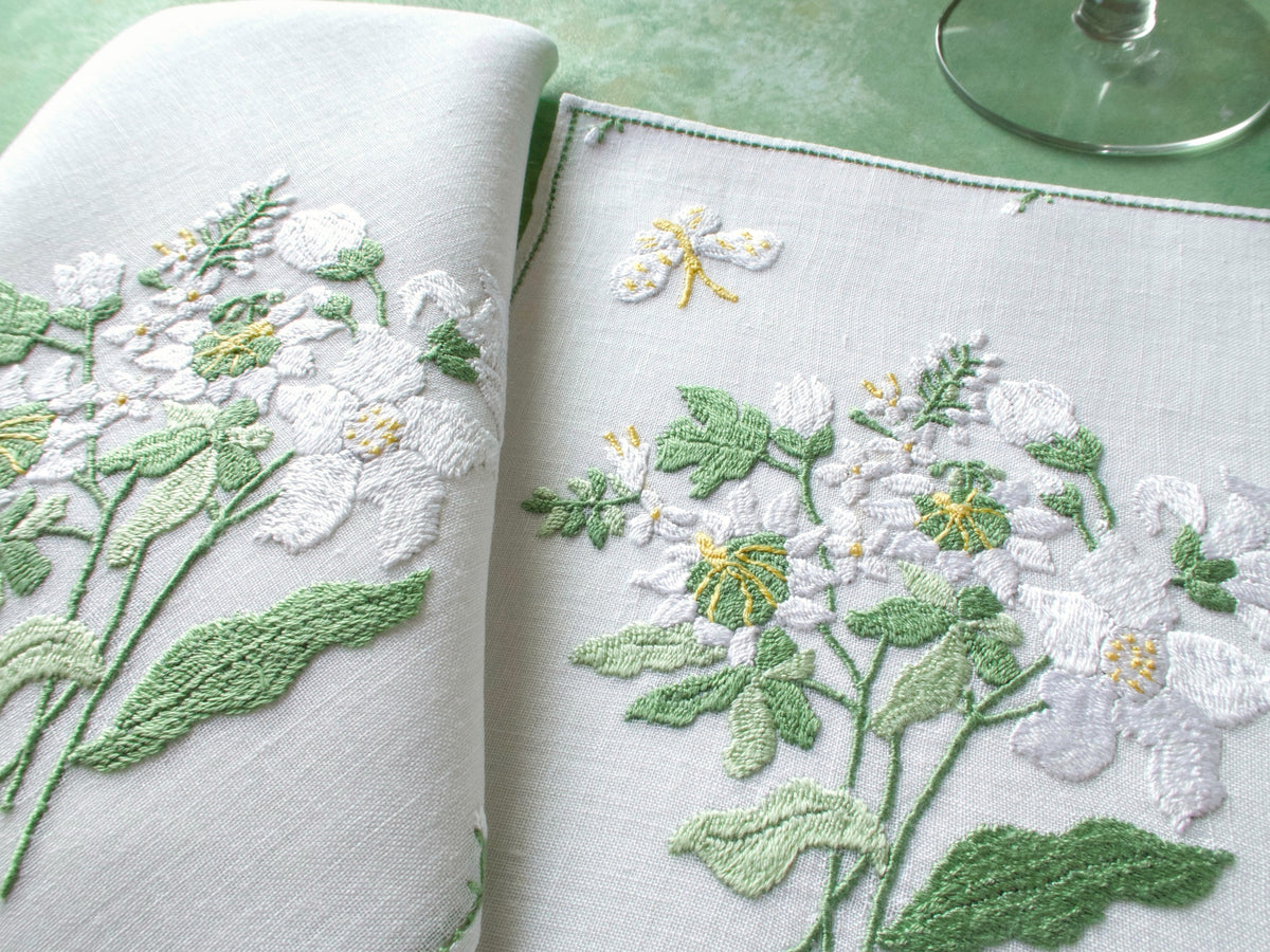 Rapisardi placemat and napkin set with white hydrangea embroidery, butterfly detail visible.