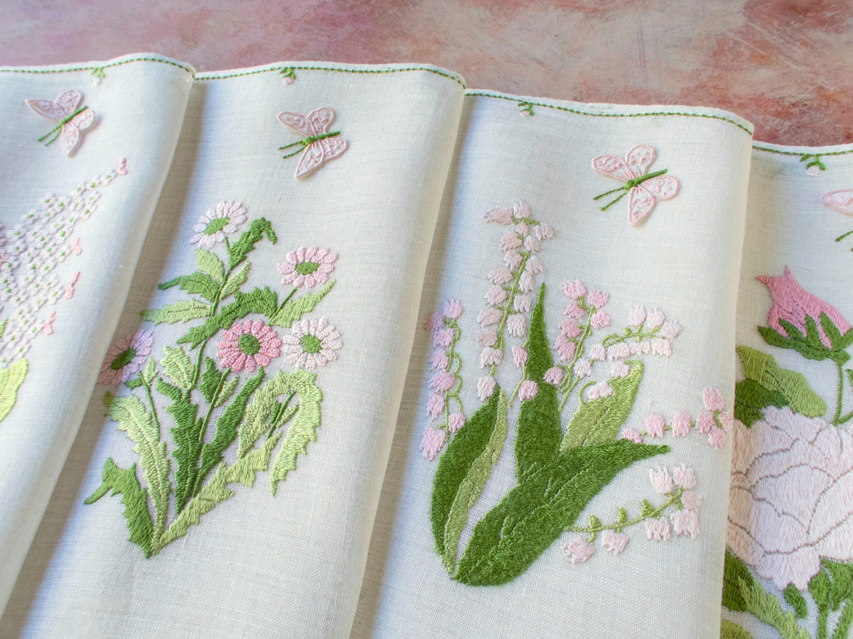 Pink Rapisardi placemats with trembler butterflies, each featuring a different embroidered flower on semi-sheer linen.
