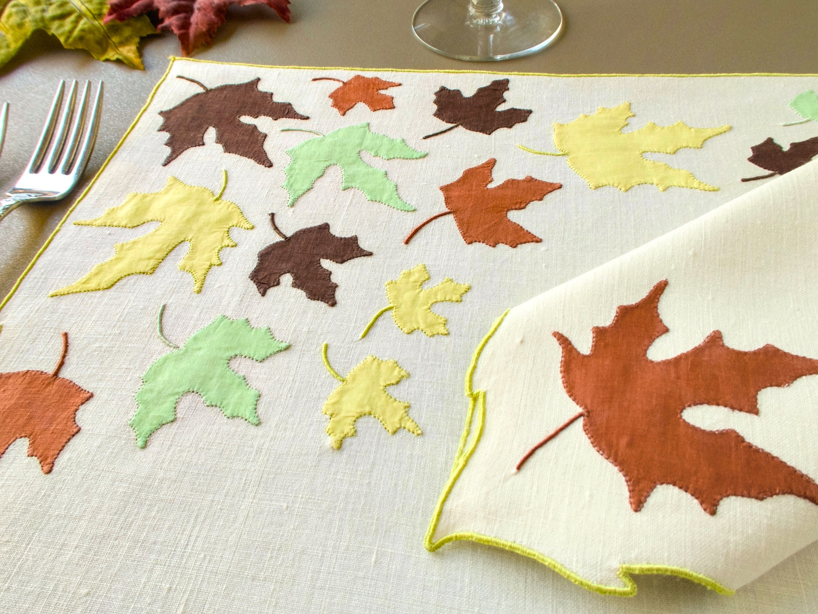 Close view of vintage Marghab "Autumn Leaves" appliqué leaves in brown, rust, pale green and yellow on linen