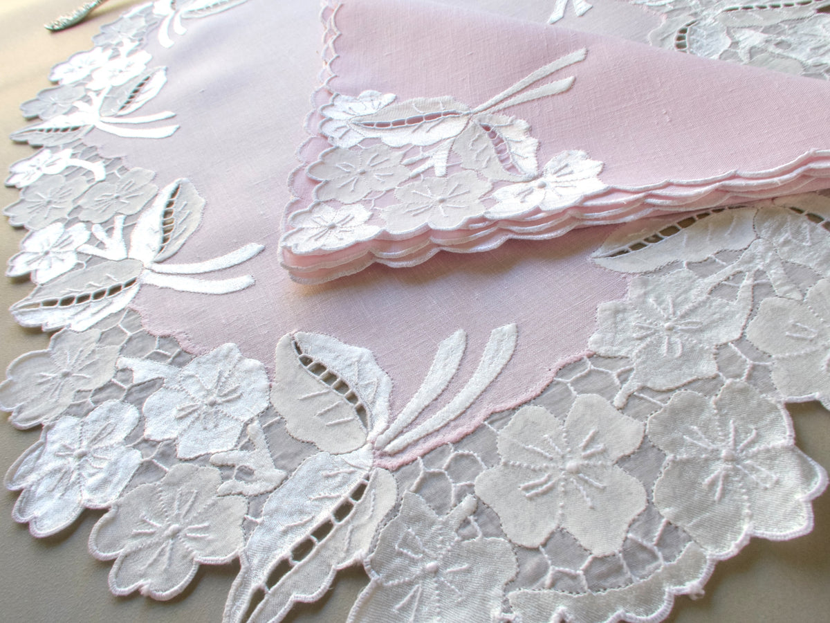 Details of a pink and white Madeira placemat with embroidered flowers, honeycomb panels and scalloped edge napkin.