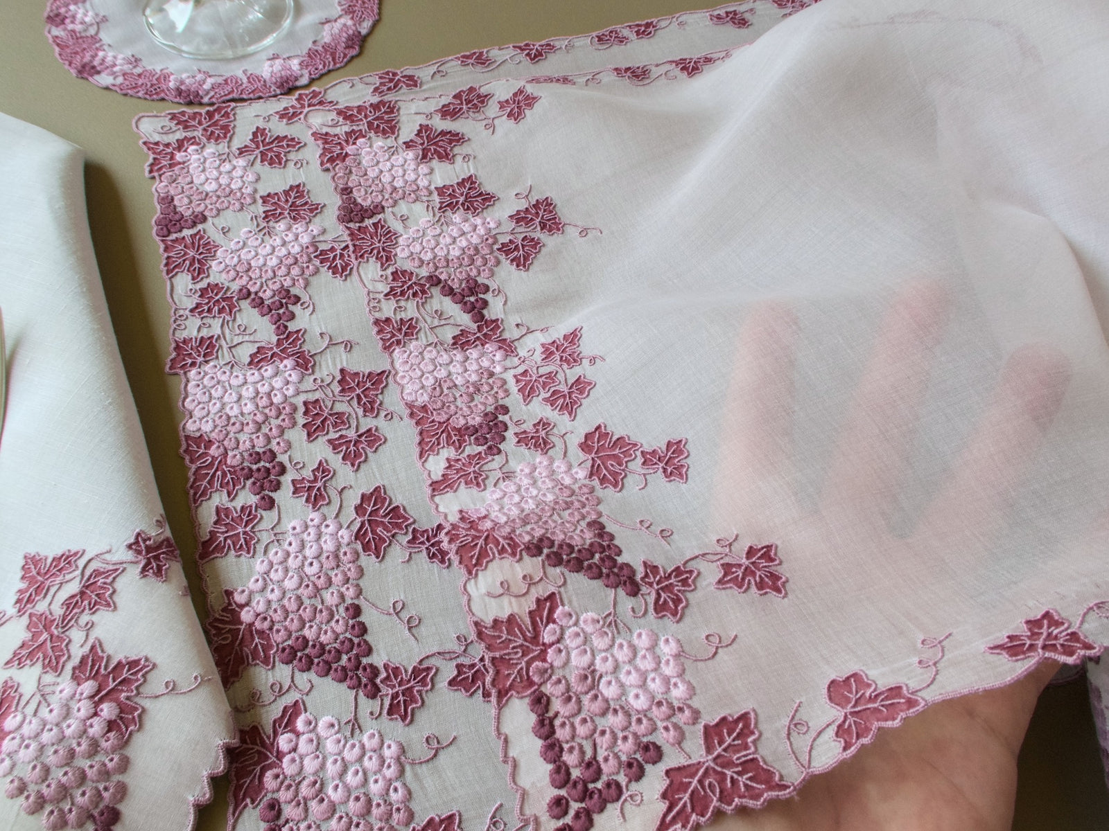 Sheer vintage Marghab Vineyard organdy placemat held up to show its transparency, with a napkin and coaster