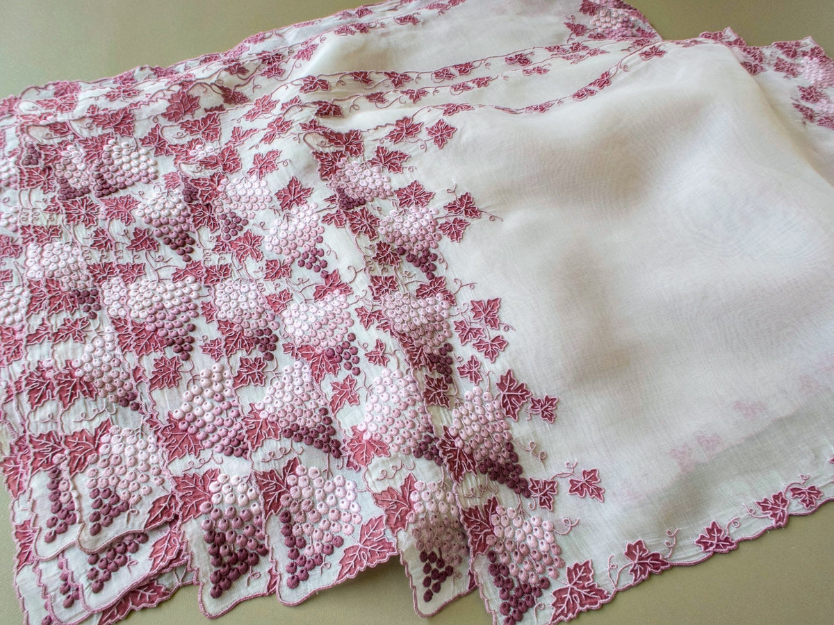Stack of vintage Marghab Vineyard placemats showing hand embroidered grape clusters along the edge