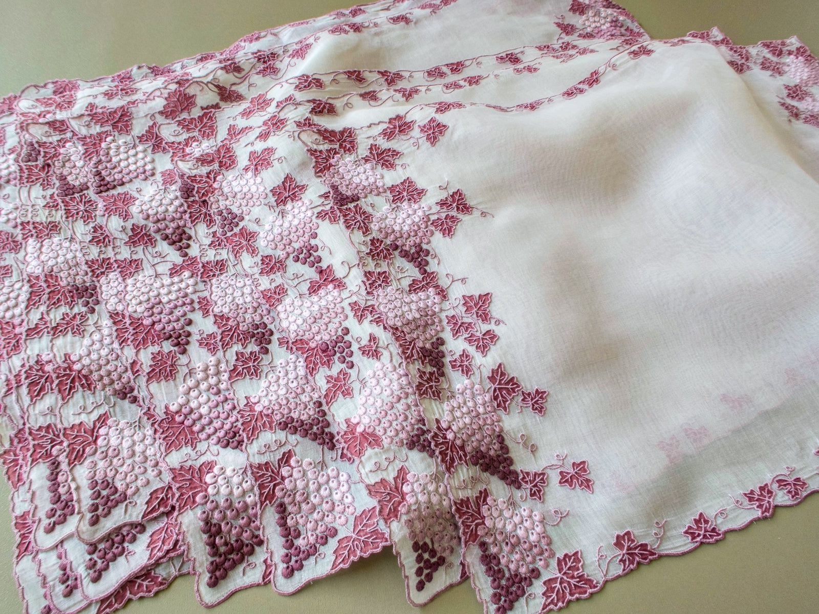 Stack of vintage Marghab Vineyard placemats showing hand embroidered grape clusters along the edge