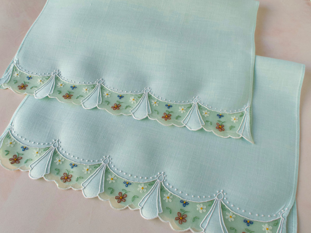 Pair of vintage Madeira guest towels in soft green folded and stacked, showing organdy swag border with tiny flower embroidery, set of 2​​​​​​​​​​​​​​​​