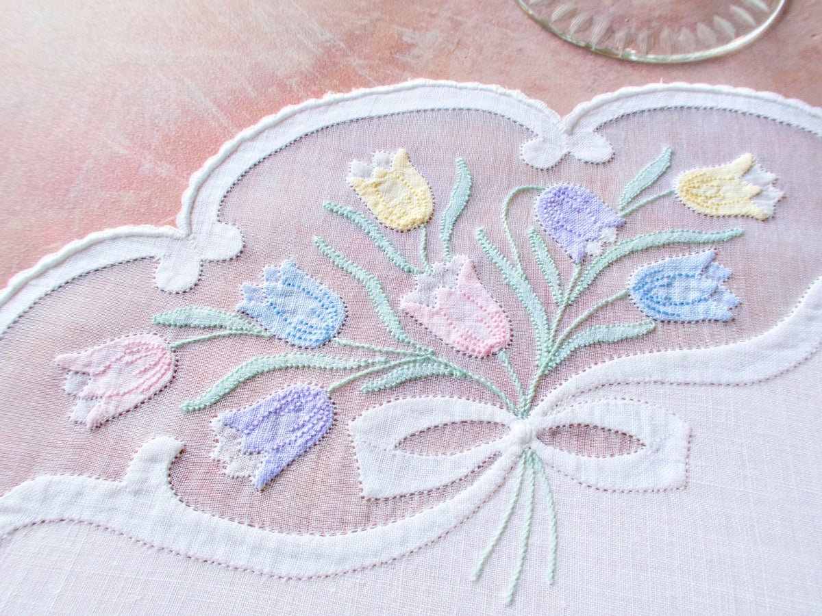 Vintage Madeira oval placemat set showing tulips and bow motif in organdy windows with decorative scalloped edges.
