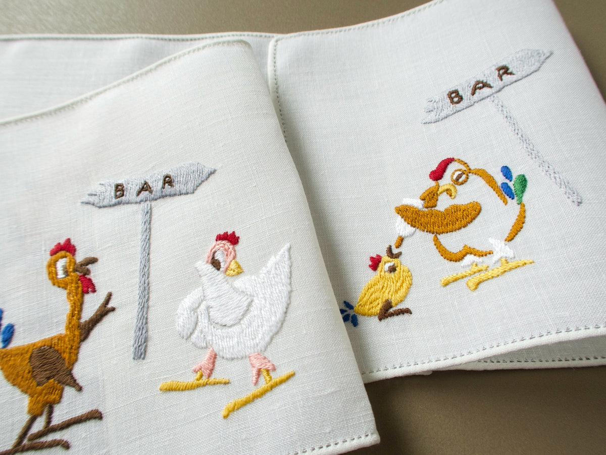 Vintage Rapisardi linen cocktail napkins folded to show hens flirting at the bar and a bleary-eyed hen feeding a bottle to a chick