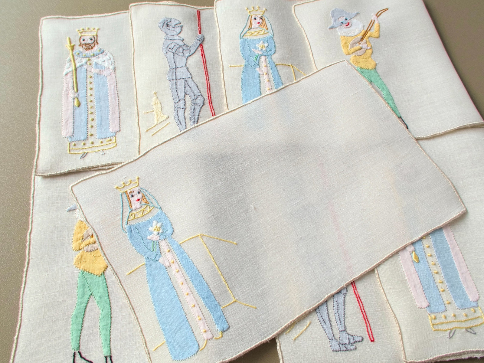 Vintage Madeira cocktail napkins fanned out, one unfolded to show the full shape, with a king, jack, queen and joker