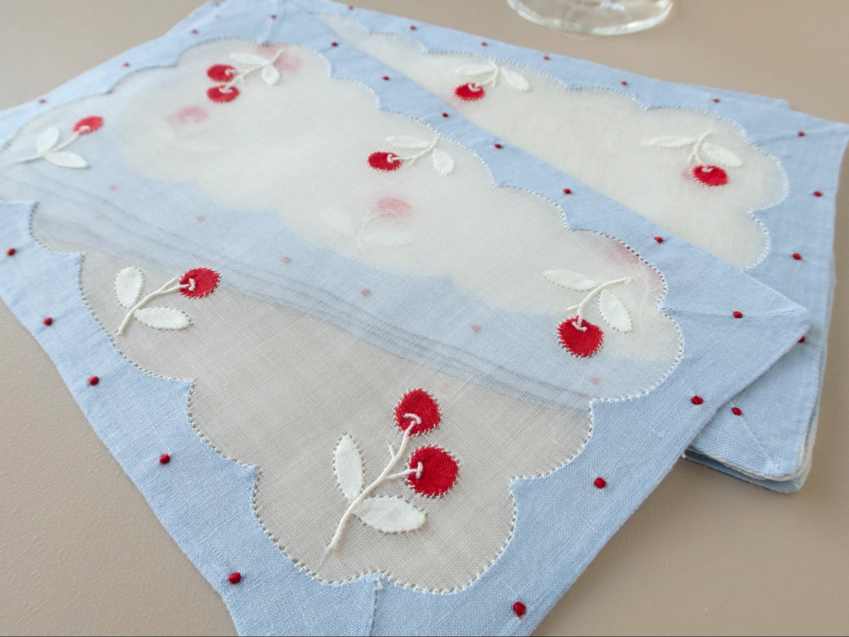 Two vintage Madeira cocktail napkins, one folded back to show the sheer organdy center and cherry appliqué