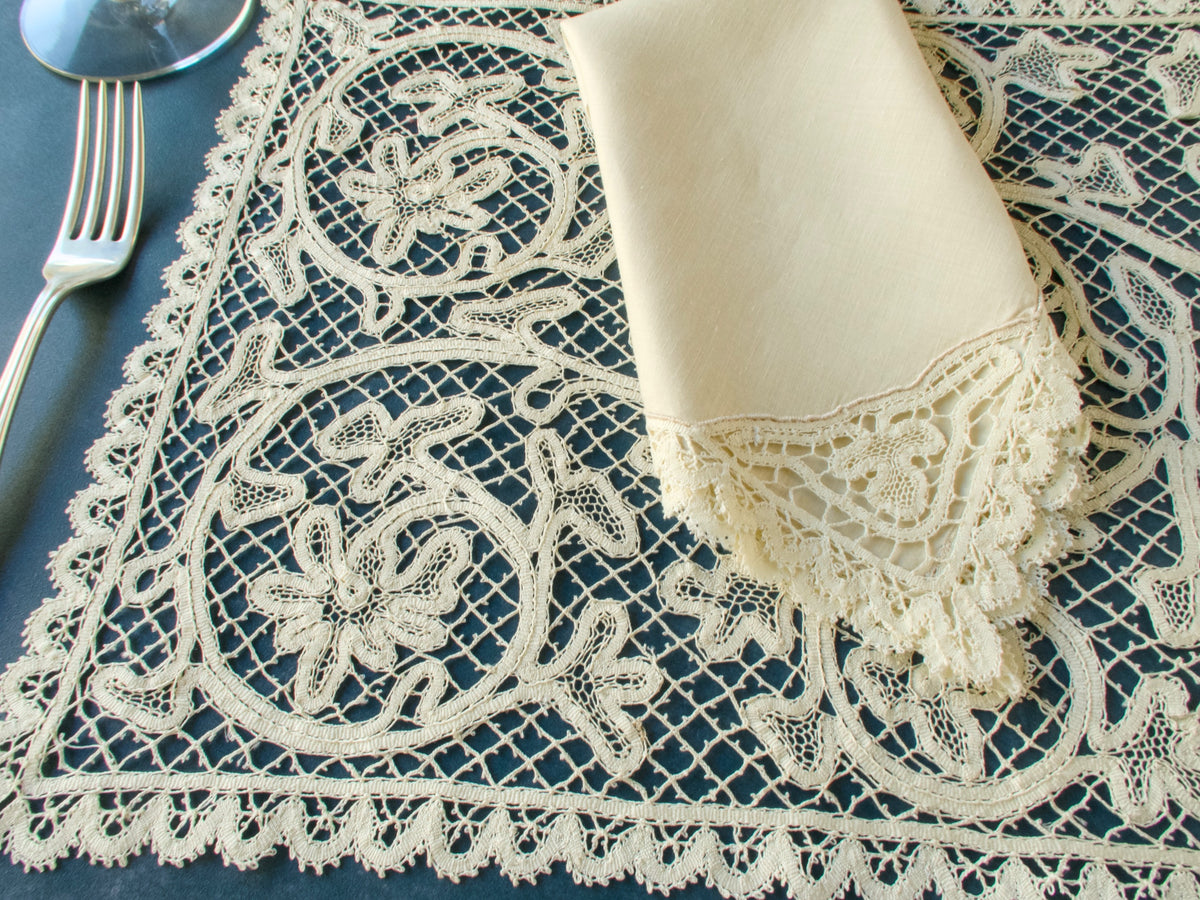 Close-up of vintage bobbin lace placemat and matching lace-edged napkin, showing detailed handmade lacework.