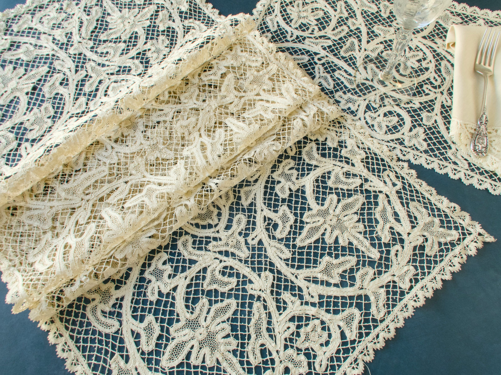 Vintage bobbin lace runner folded to show lace edge detail and dense handmade lacework construction.