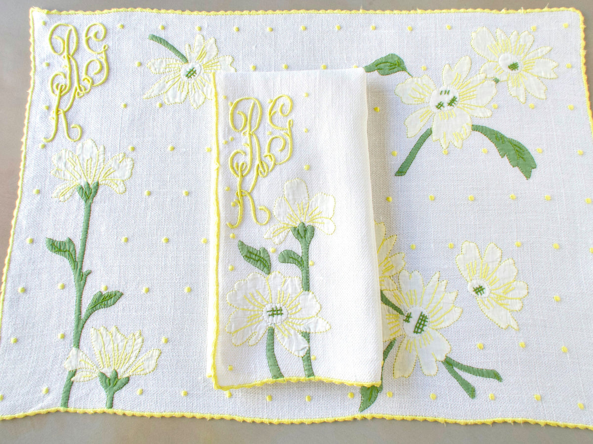 Madeira embroidered placemat and folded napkin showing full daisy and dot work design with yellow edging and monogram