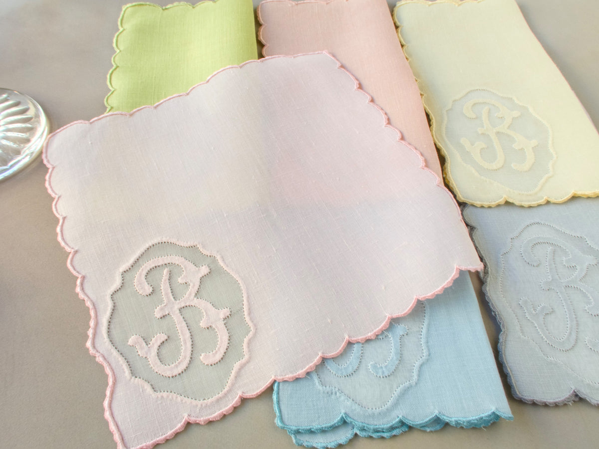 Single vintage Madeira Irish linen cocktail napkin hand embroidered with cursive “B” monogram in organdy window and scalloped edging, in pale pastel linen​​​​​​​​​​​​​​​​