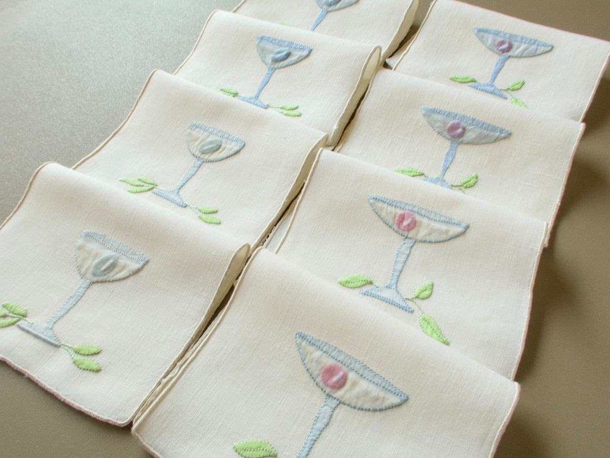 Set of 8 vintage Madeira cocktail napkins folded in rows, each with an appliquéd glass and leaves