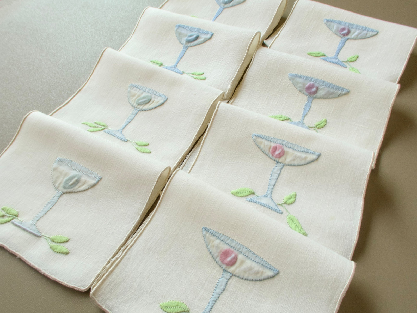 Set of 8 vintage Madeira cocktail napkins folded in rows, each with an appliquéd glass and leaves