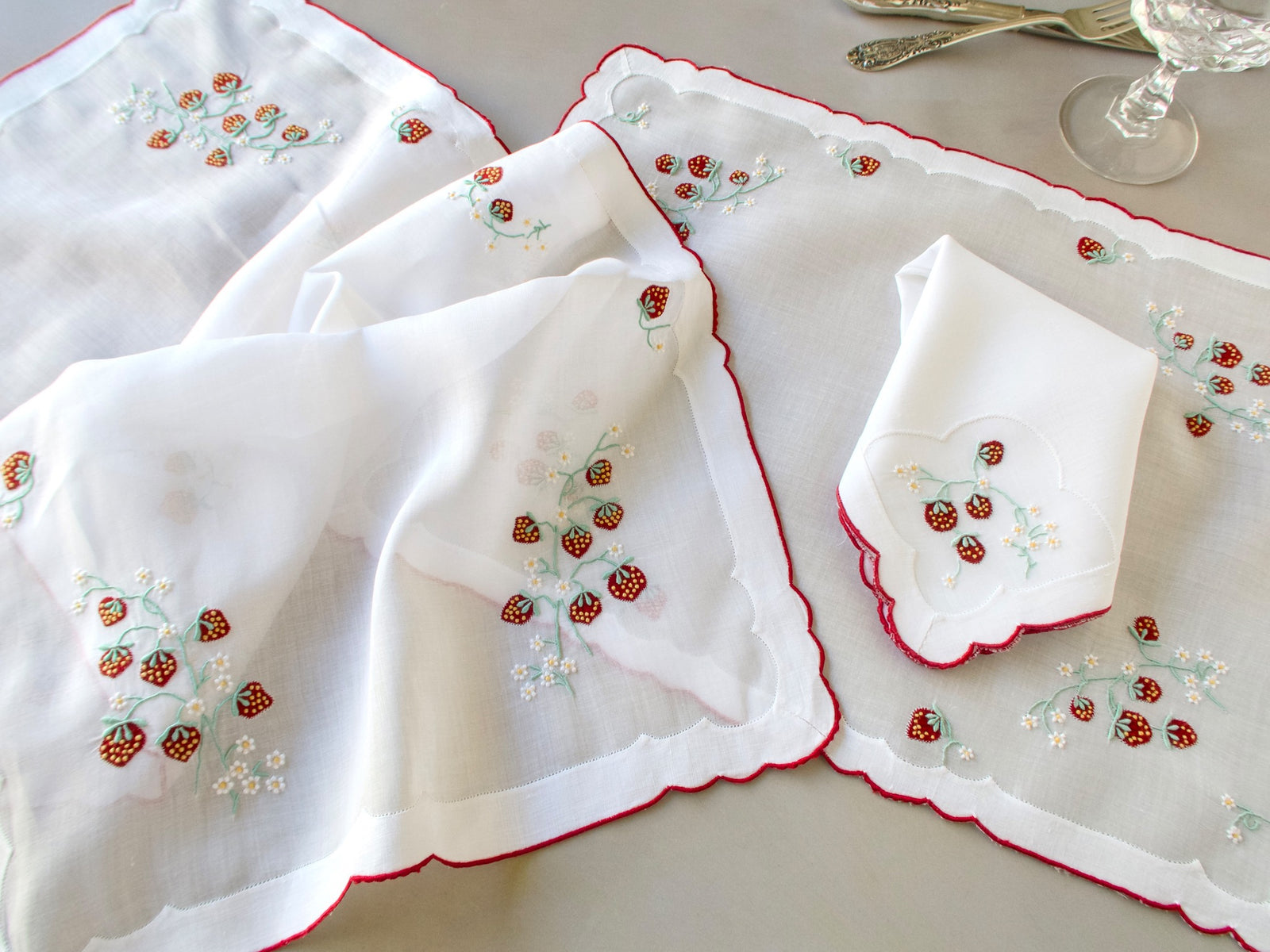 Vintage Madeira organdy table runner showing scattered red strawberry and white daisy embroidery with red scalloped border​​​​​​​​​​​​​​​​