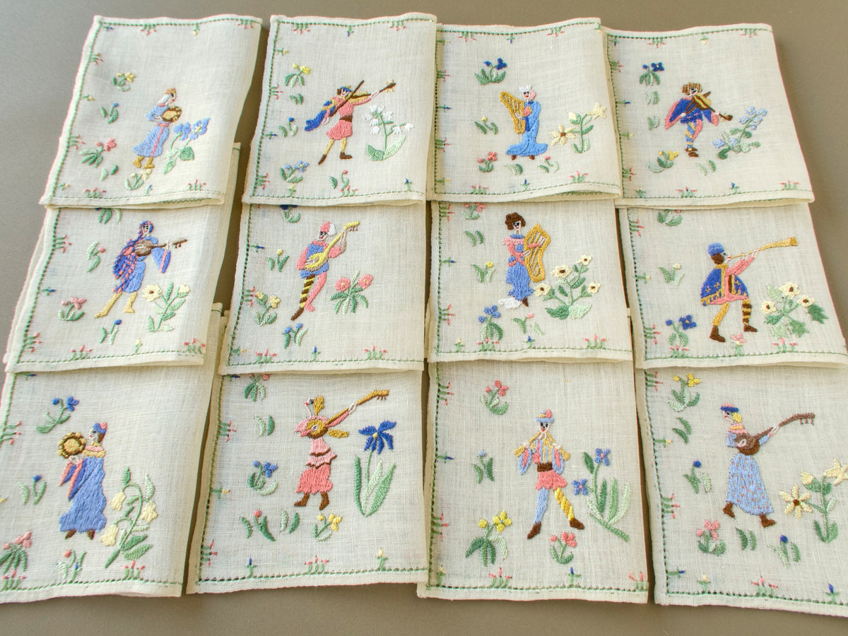 Set of 12 folded vintage Baroness Rapisardi Medieval Musicians cocktail napkins in three rows, each embroidered in punto stuoia with a different figure playing a harp, lute, violin, tambourine, horn or pipes among flowers