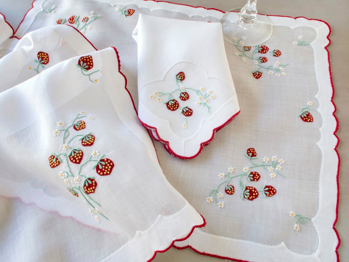 Vintage Madeira linen napkin on organdy placemat showing red strawberry embroidery detail and edge of organdy runner with red scalloped border