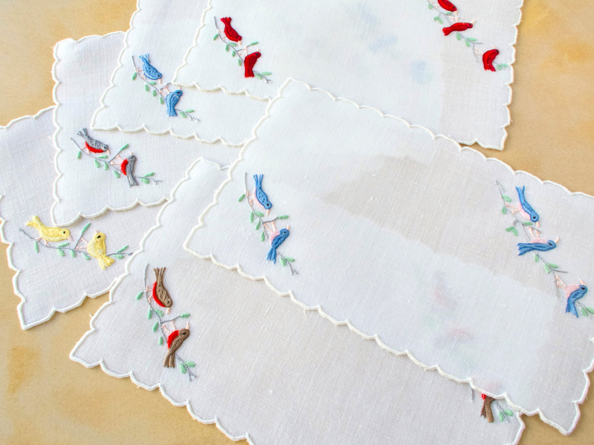 Set of six vintage Madeira linen cocktail napkins featuring red, yellow and blue embroidered birds.