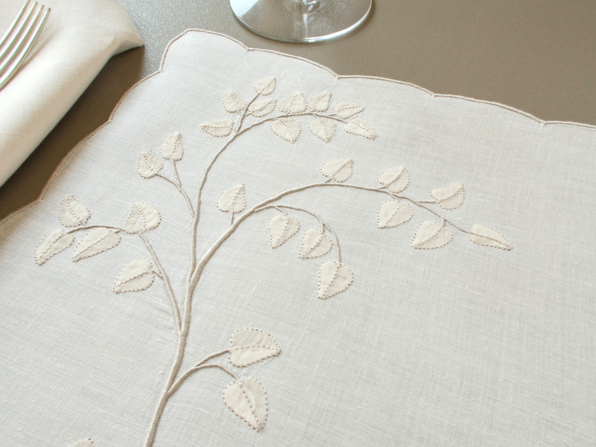 Close view of appliquéd leaves and embroidered branches on a vintage Madeira linen placemat