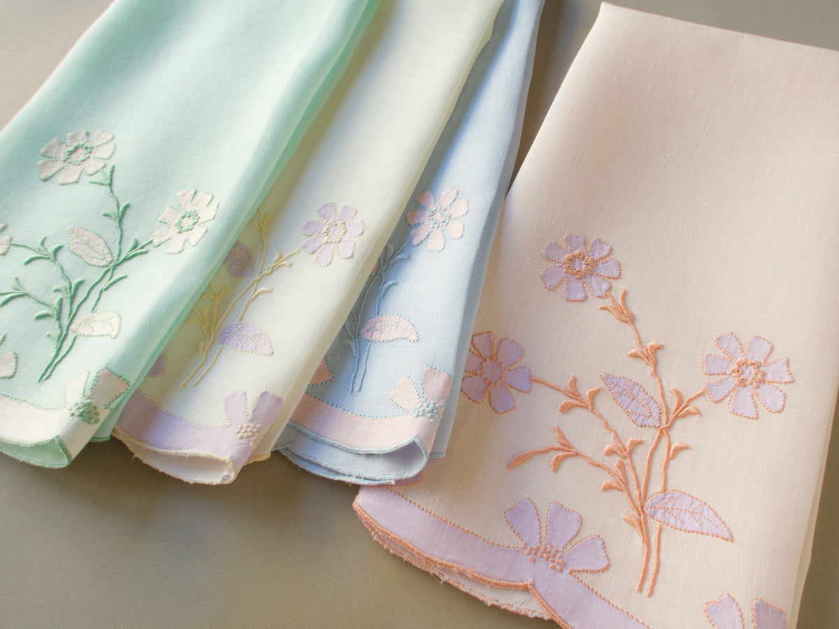 Set of four vintage Madeira guest towels hand embroidered on fine Irish linen, fanned out to show delicate floral sprays in coordinating pastel colors — peach, lavender, blue and green