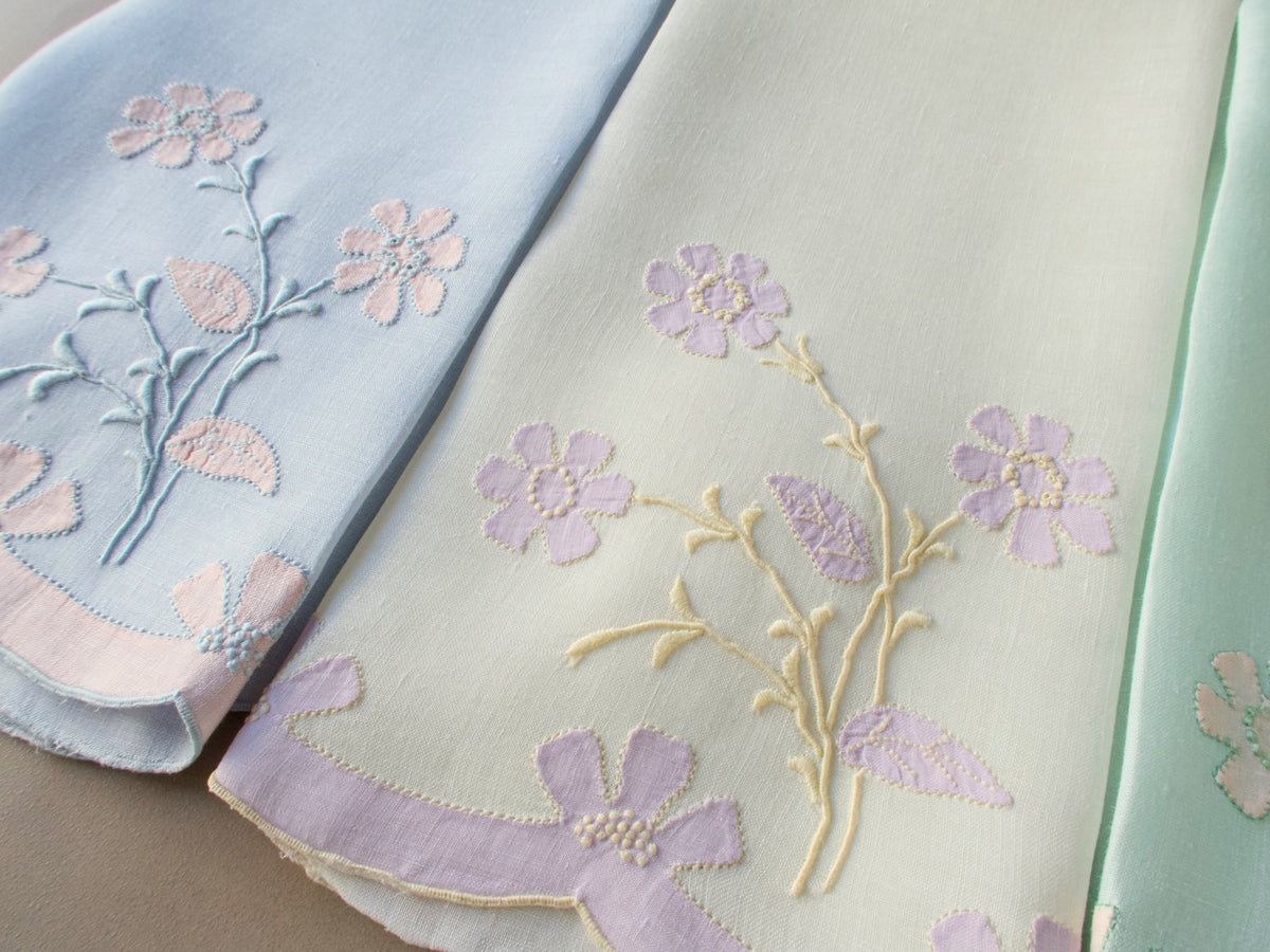 Close-up of two vintage Madeira guest towels hand embroidered with matching floral motifs in lavender and soft blue on featherweight Irish linen