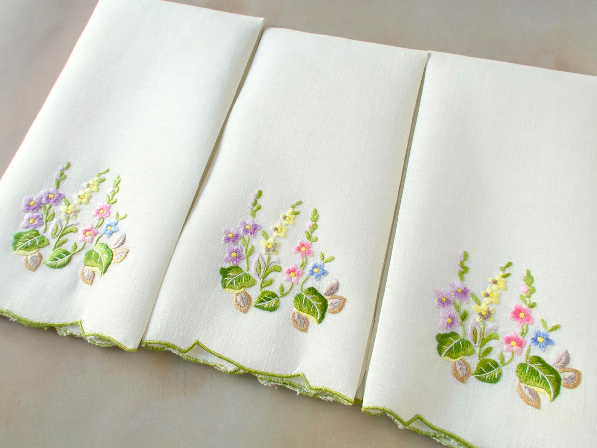 Overhead view of vintage Belgian linen guest towels, hand embroidered in Madeira with colorful floral bouquet and scalloped edge.