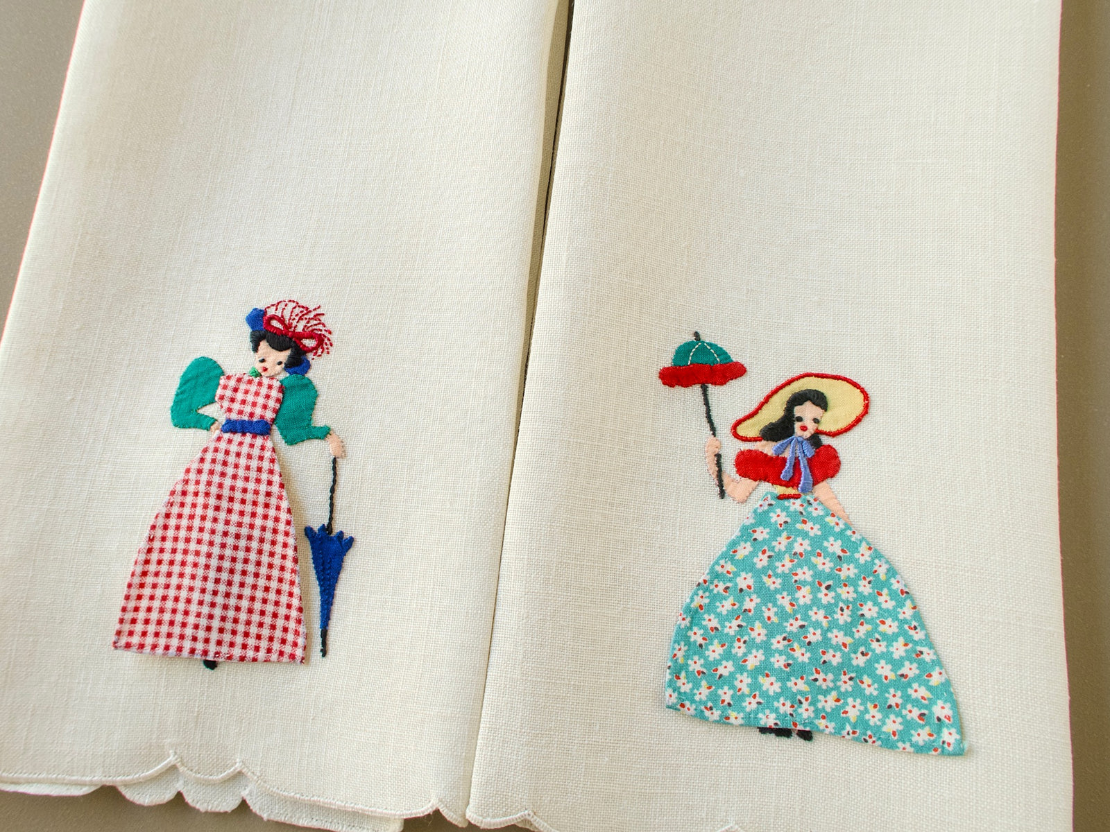 Pair of vintage Madeira linen guest towels with appliquéd ladies in gingham and floral dresses, one holding a parasol
