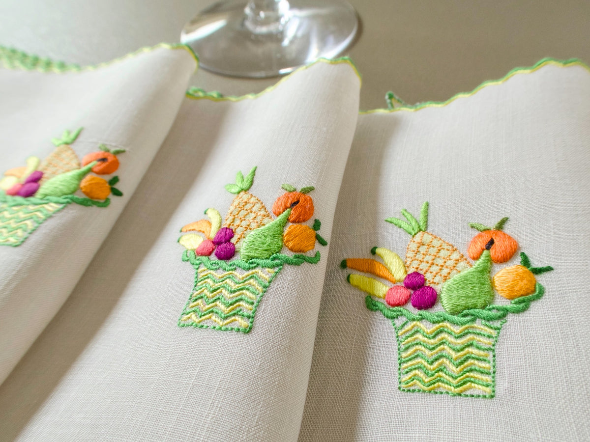 Three vintage Marghab “Fruit Basket” linen cocktail napkins with richly colored hand embroidered fruit baskets and distinctive green and yellow double-stitched hem treatment.