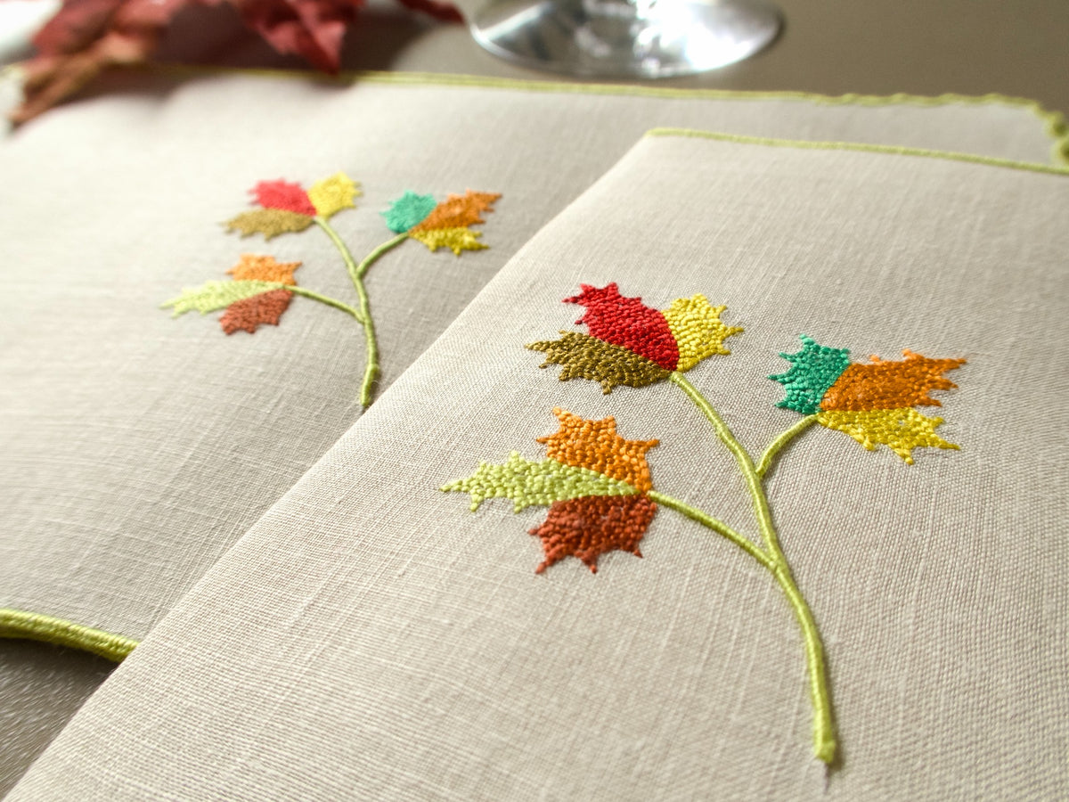 Close view of vintage Marghab “Maple Leaf” linen cocktail napkins with hand embroidered autumn leaves in red, gold, orange, green and brown.