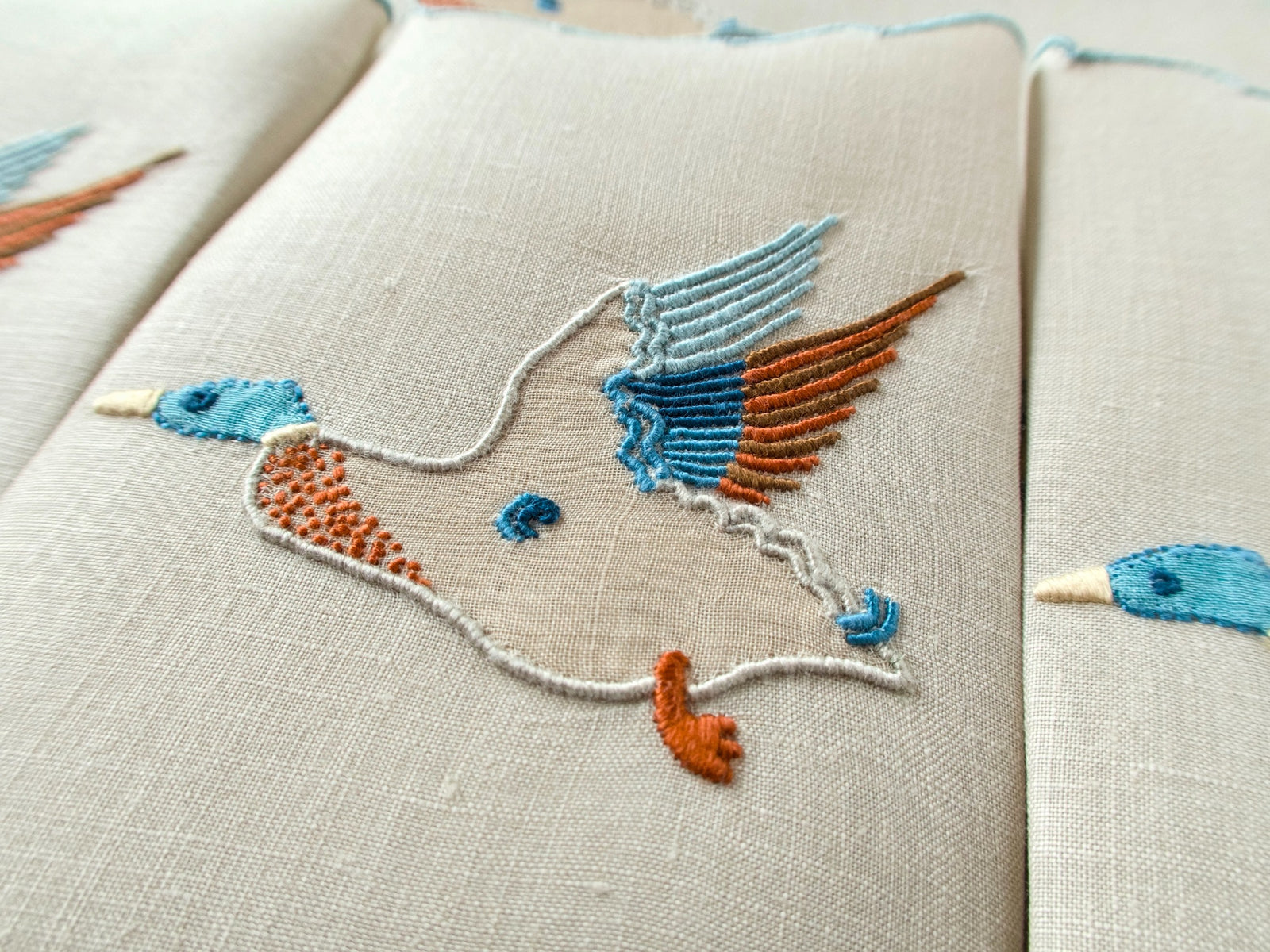 Vintage Marghab Wild Duck cocktail napkin with hand embroidered blue and rust duck in flight on ivory linen