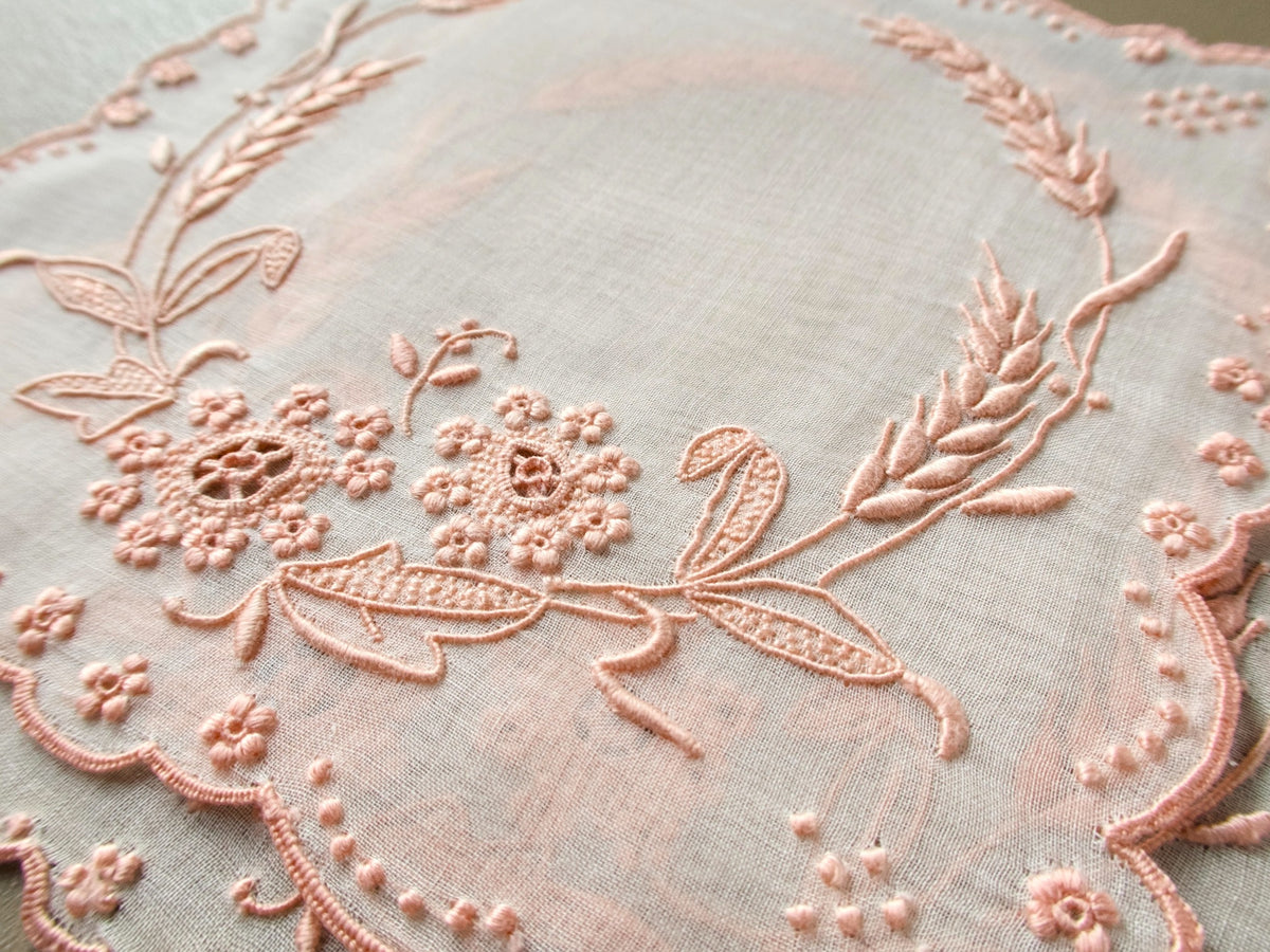 Close view of a vintage Marghab “Wheat” organdy cocktail napkin showing fine pink Madeira embroidery, wheat sprays and floral details.