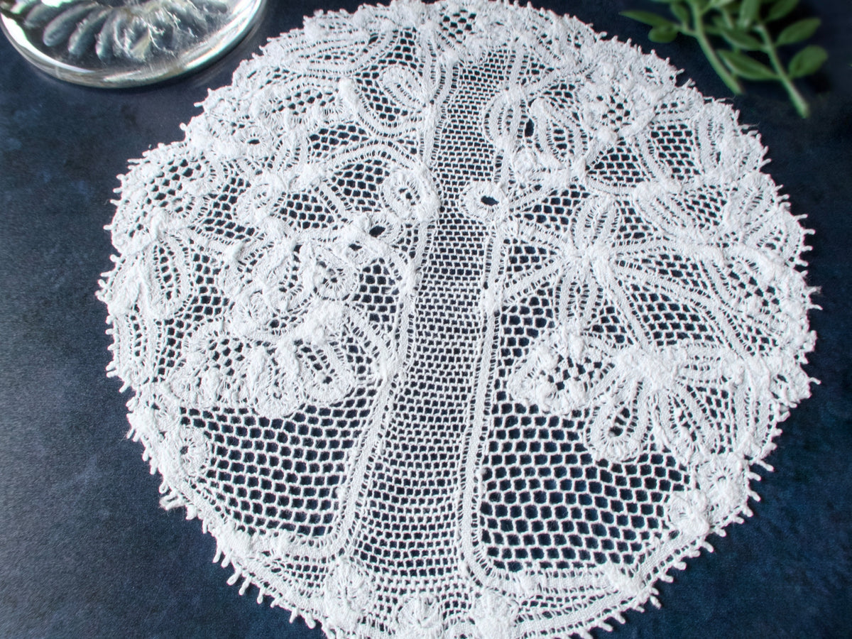 Vintage Renaissance lace cocktail round featuring an intricate stylized tree motif in ivory white, shown against a dark background