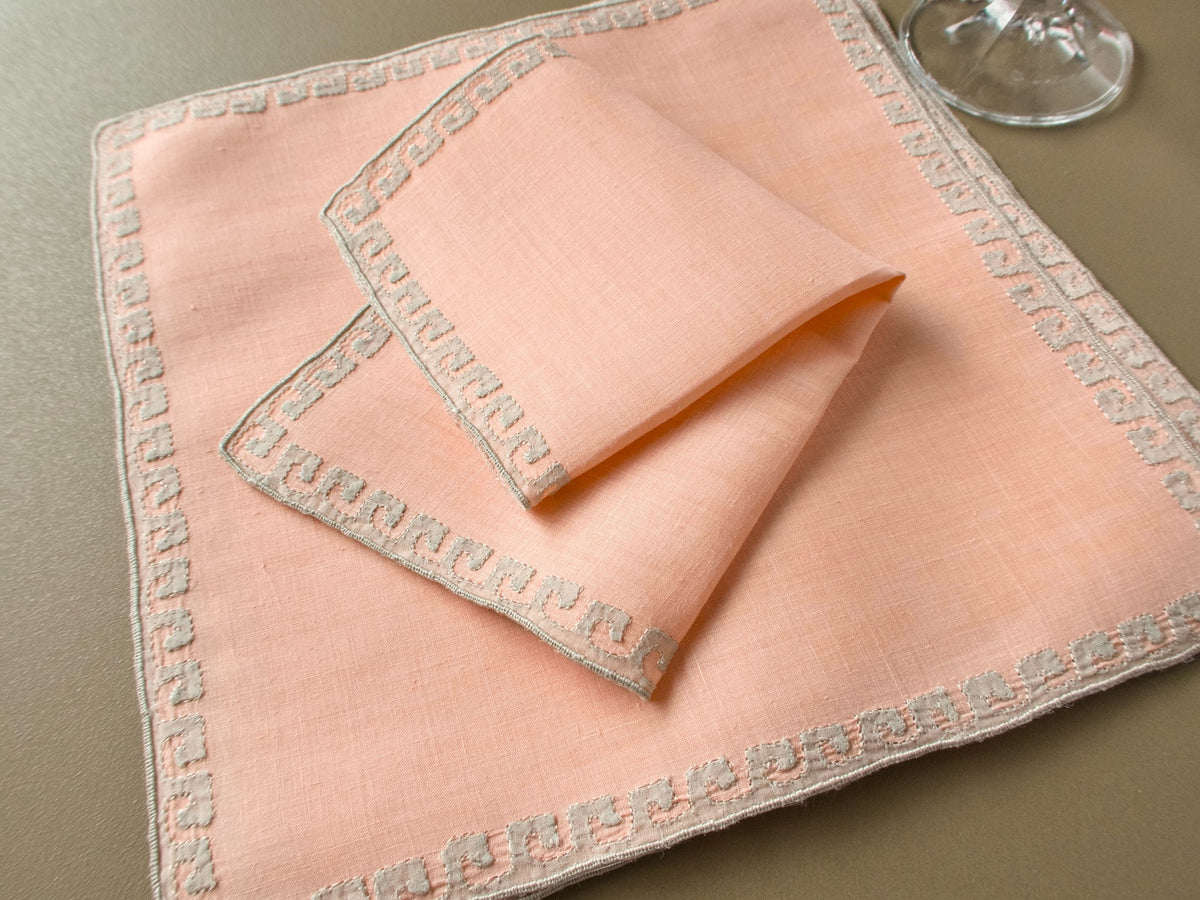 Vintage Marghab “Grecian Border” coral linen cocktail napkins with pale embroidered Greek key borders and a wine glass.