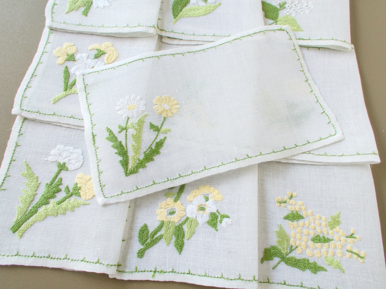 Baroness Rapisardi vintage cocktail napkin opened flat to show the semi-sheer linen, with floral embroidered  napkins folded behind it