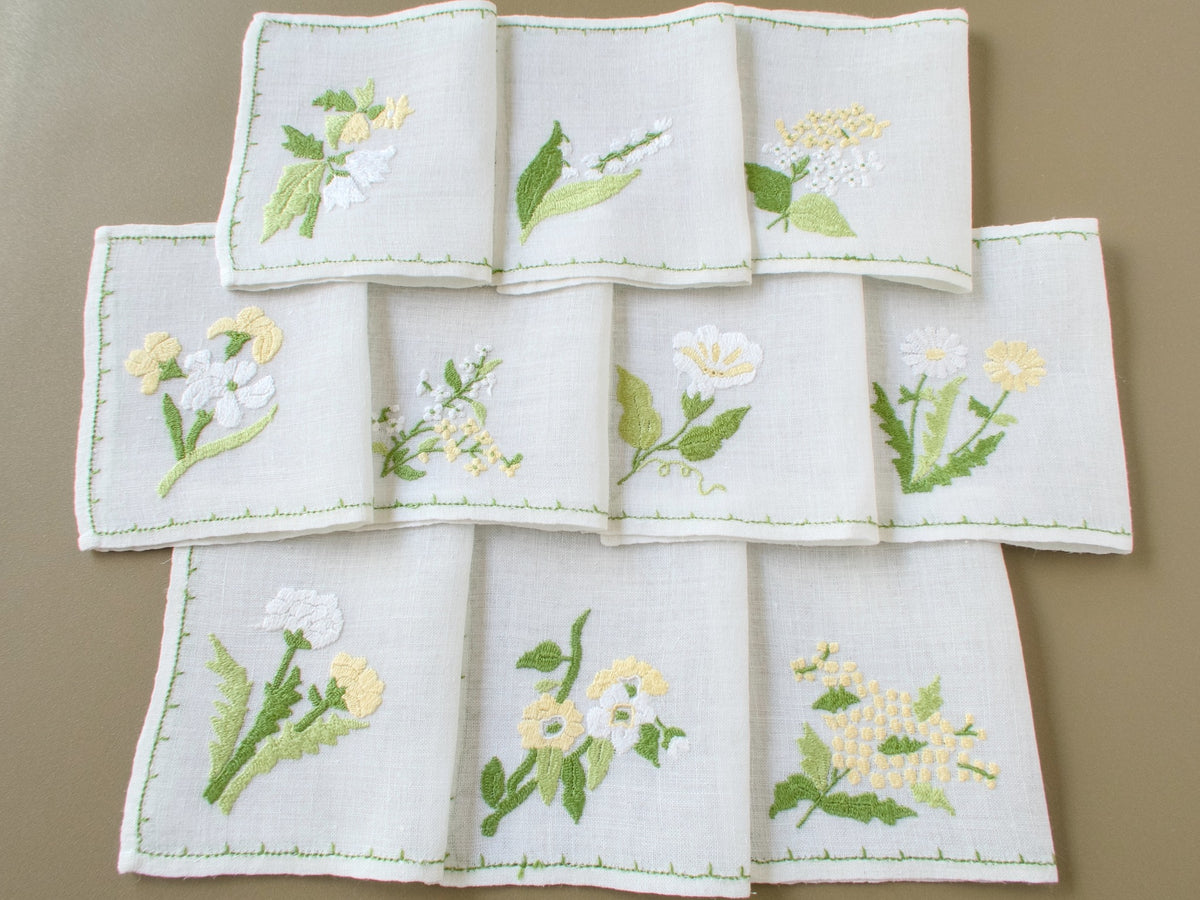 Set of ten vintage Baroness Rapisardi floral cocktail napkins, each hand embroidered with a different flower in yellow, white and green.