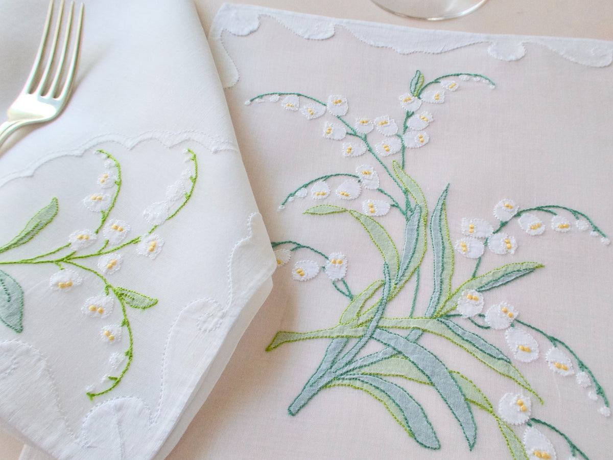 Detail of cascading Lily of the Valley embroidery with raised white blossoms and yellow centers on vintage organdy placemat.