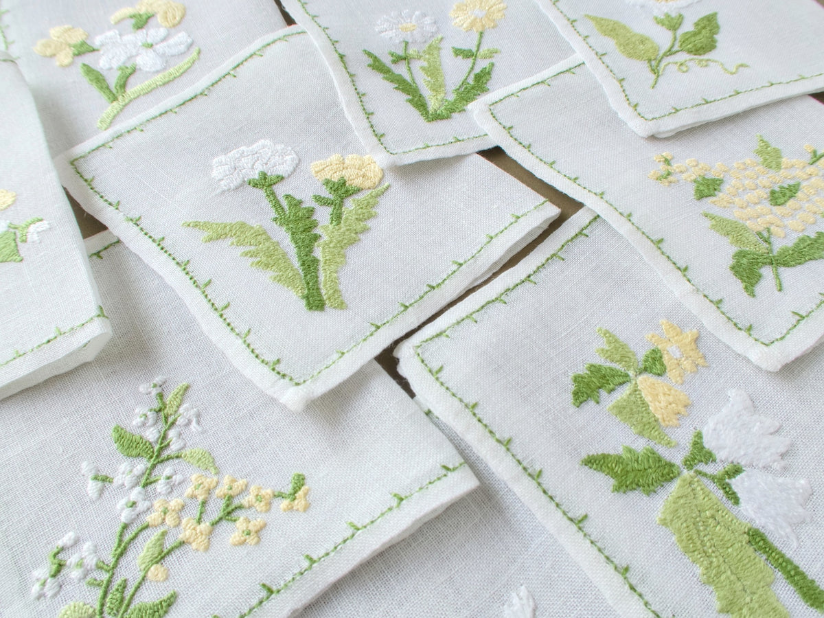 Baroness Rapisardi floral cocktail napkins arranged to show the variety of hand embroidered flower motifs and fine semi-sheer linen.