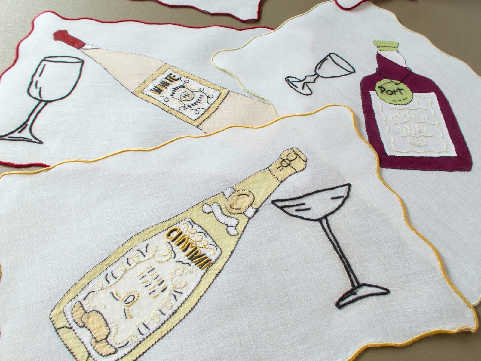 Vintage Madeira cocktail napkins with appliqué white wine, port and champagne bottles and embroidered glasses on linen