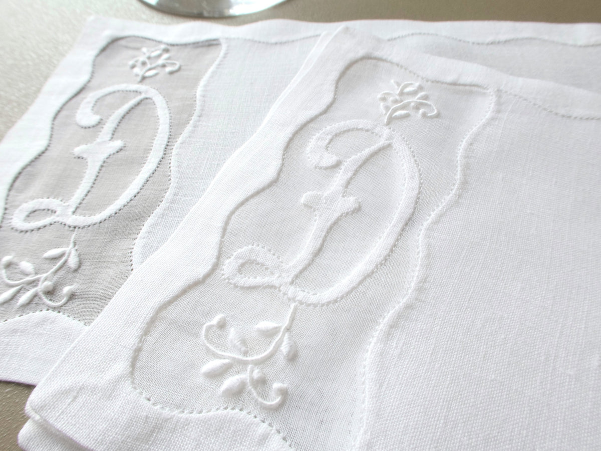 Two vintage Madeira linen cocktail napkins with an embroidered D monogram in a scalloped organdy window