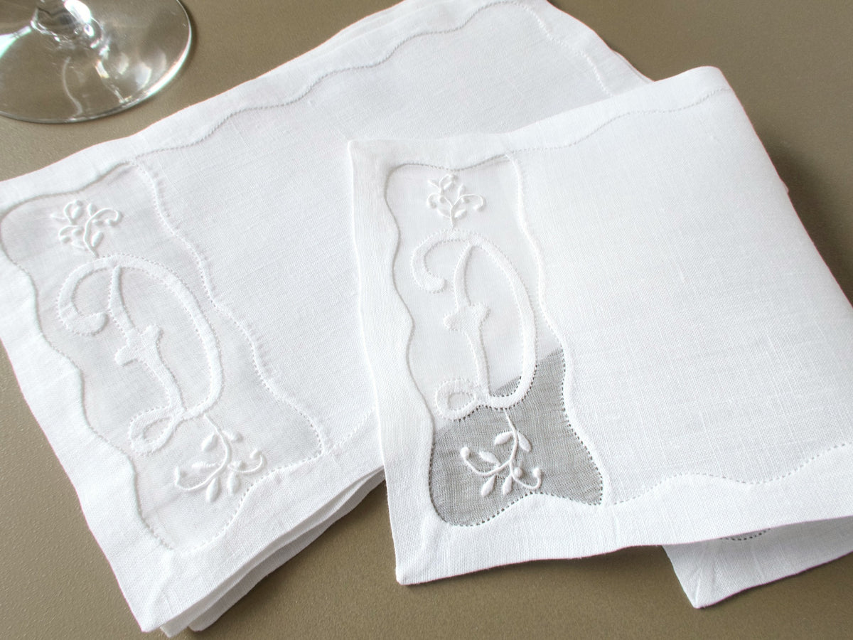 Stack of vintage Madeira linen cocktail napkins with D monograms beside a wine glass