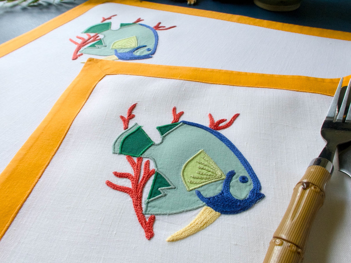 green fish embroidered on a linen placemat