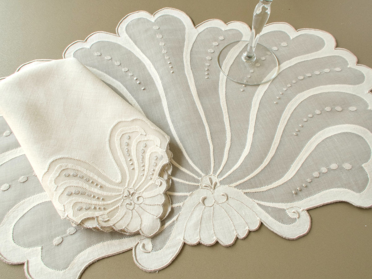 Vintage Madeira fan-shaped placemat with a napkin corner repeating the fan motif and a wine glass resting on the organdy