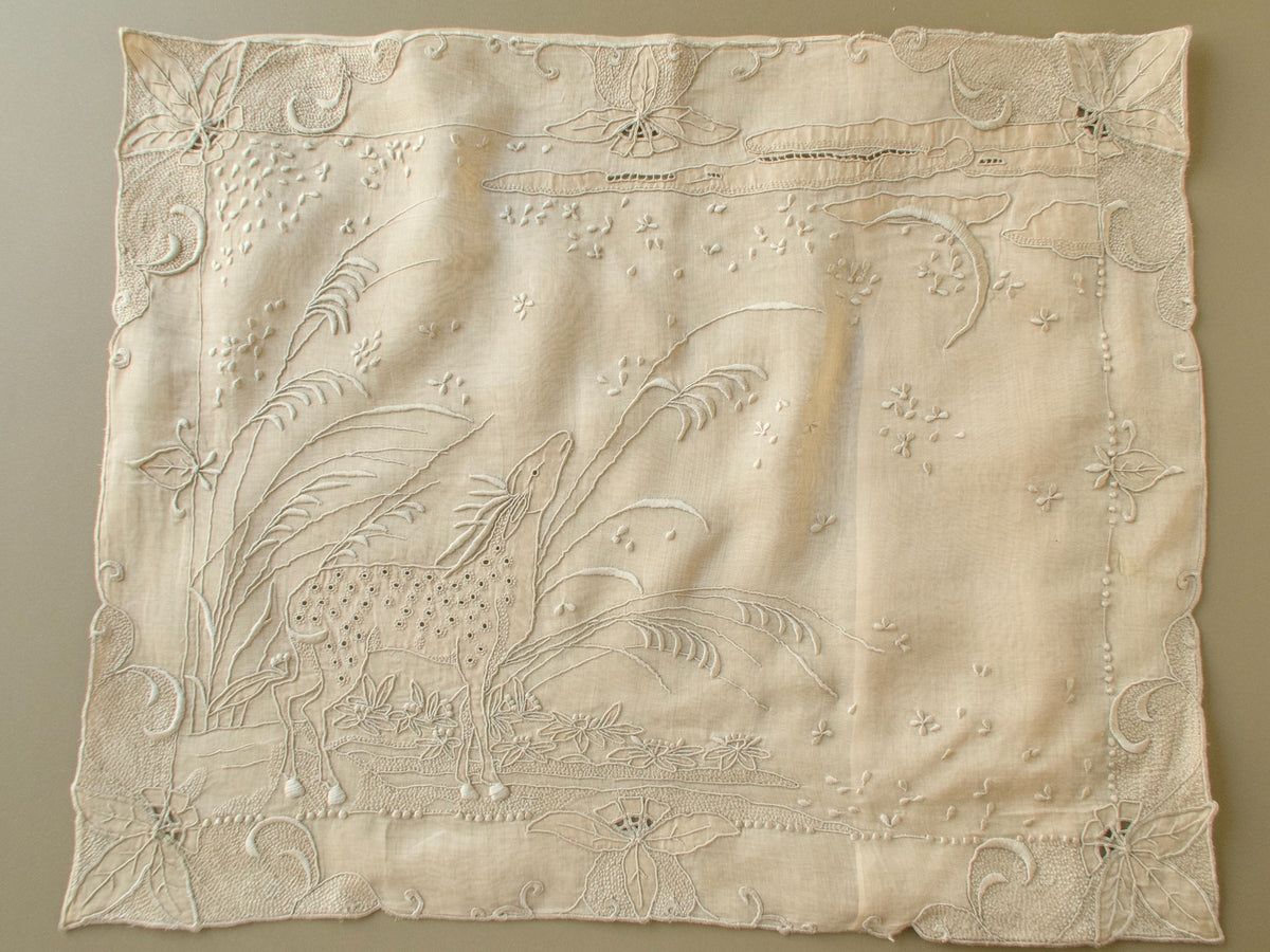 Full front of a vintage Marghab "Deer" organdy pillow cover with a hand embroidered deer beneath a crescent moon and a scroll border
