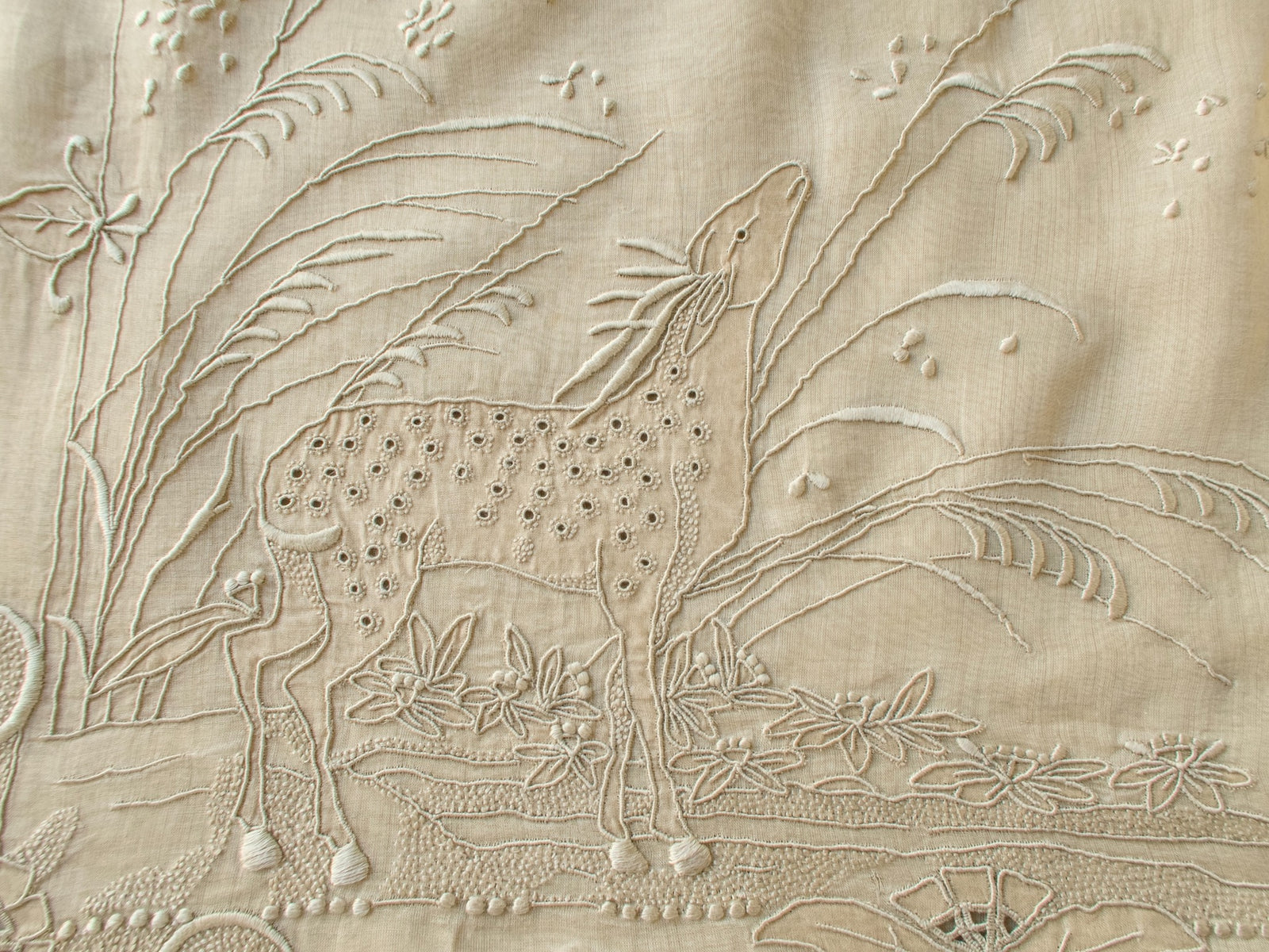 Close view of the hand embroidered deer on a vintage Marghab organdy pillow cover, with eyelet spots and raised grasses