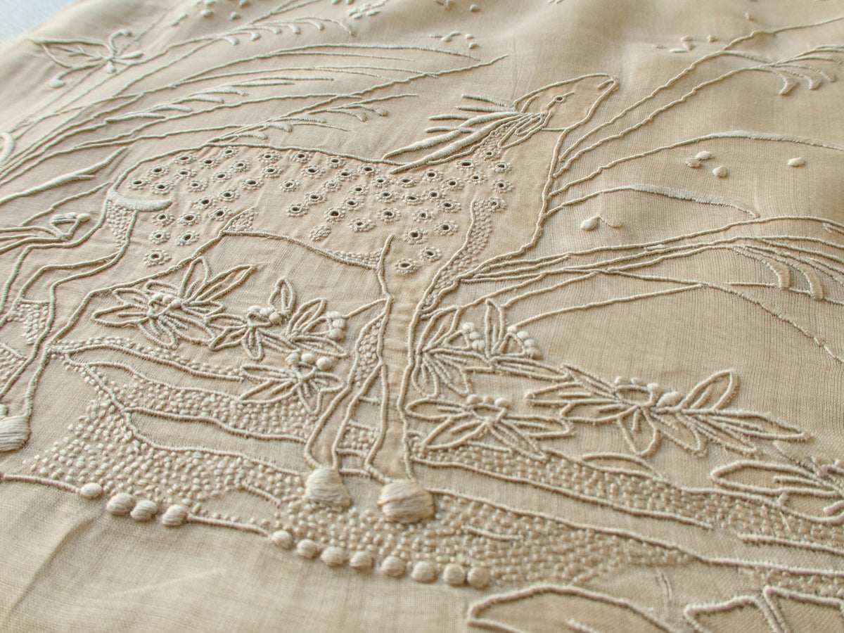 Close view of the hand embroidered deer on a vintage Marghab organdy pillow cover, with eyelet spots and raised grasses