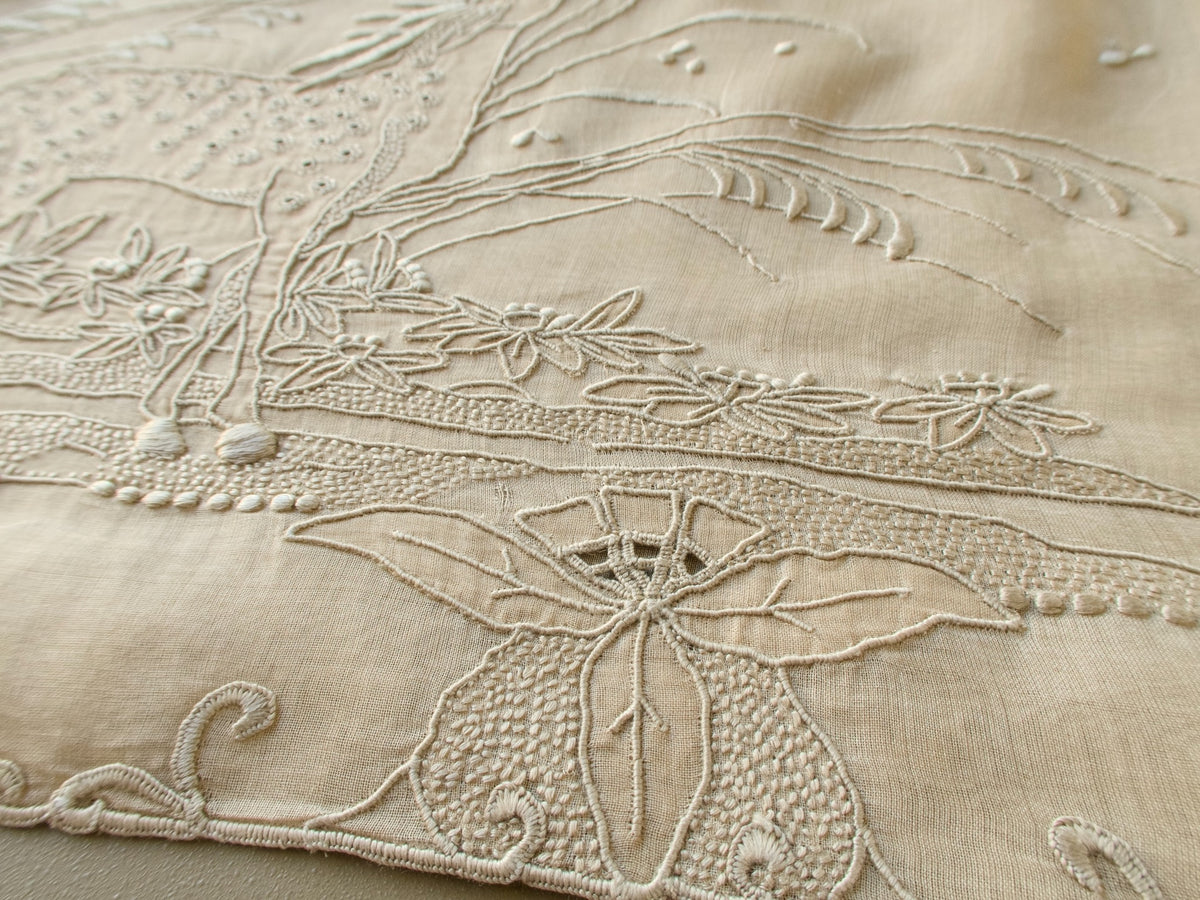 Angled view of the raised embroidery at the deer's hooves and flowers on a vintage Marghab organdy pillow cover