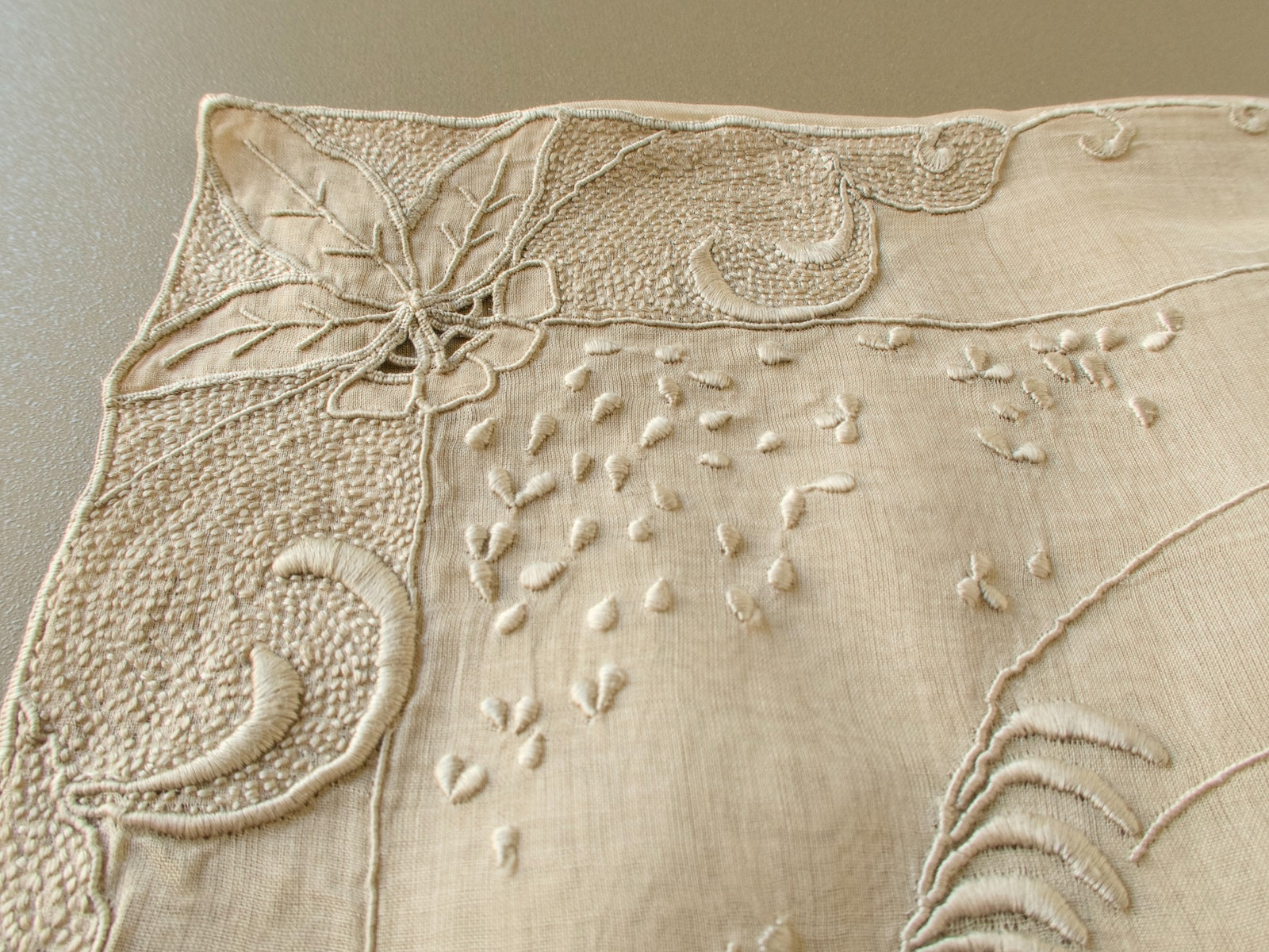 Corner of a vintage Marghab "Deer" organdy pillow cover with a densely stitched leaf and scroll border