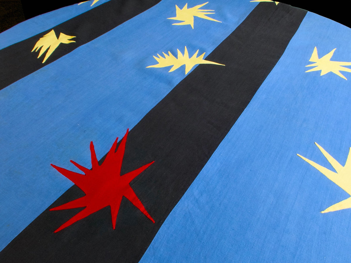 Detail of the Porthault ‘Cirque’ tablecloth showing red and yellow star motifs against blue and black linen.