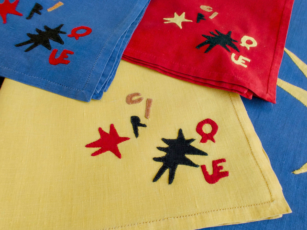 Assorted Porthault ‘Cirque’ linens showing vivid mid-century palette of red, yellow, blue, and black with abstract motifs.